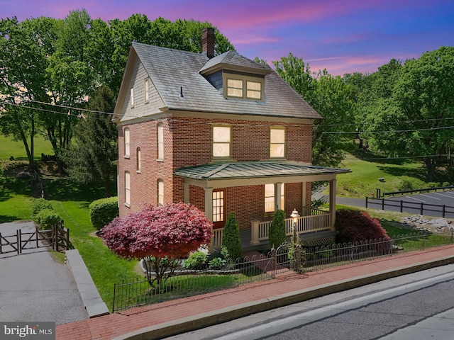 view of front of home with a chimney, brick siding, a fenced front yard, a porch, and a gate