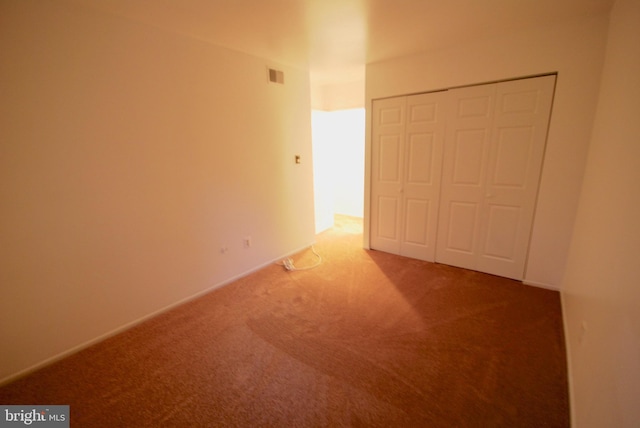unfurnished bedroom with a closet, visible vents, and carpet floors