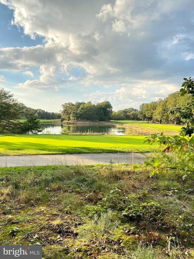 view of community with a yard, view of golf course, and a water view