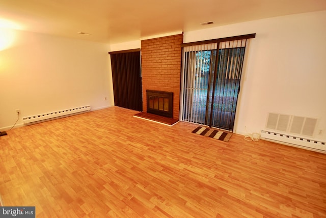 unfurnished living room with wood finished floors, a baseboard heating unit, visible vents, a brick fireplace, and baseboards