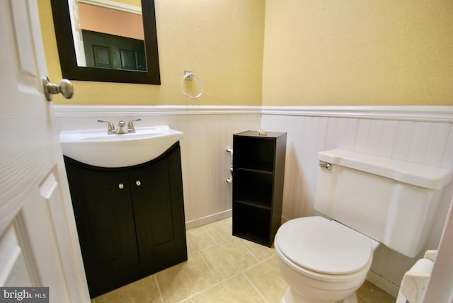 bathroom with vanity, toilet, a wainscoted wall, and tile patterned flooring