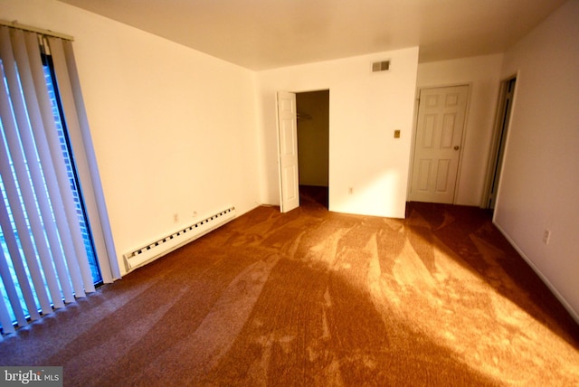 unfurnished bedroom with visible vents, a baseboard heating unit, and carpet floors