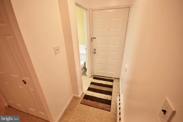 doorway to outside featuring baseboards and light tile patterned flooring