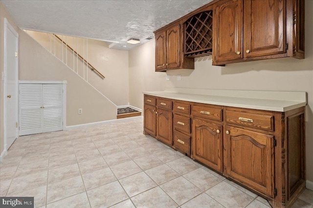 8513 Bound Brook Ln, Alexandria, VA 22309 - kitchen featuring brown cabinetry, light countertops, baseboards, a textured ceiling, and light tile patterned floors