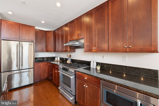 1418 N Rhodes St Unit B401, Arlington, VA 22209 - kitchen with high end appliances, under cabinet range hood, dark stone counters, dark wood-style flooring, and recessed lighting
