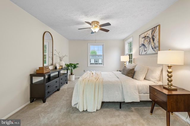 bedroom featuring carpet, a textured ceiling, baseboards, and ceiling fan