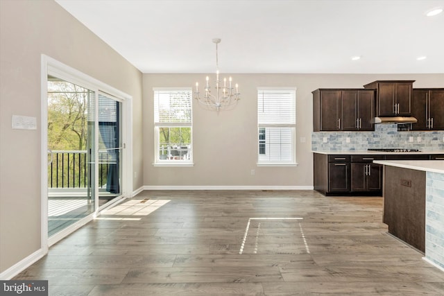 5609 Zoe Ln, Frederick, MD 21704 - kitchen with gas cooktop, under cabinet range hood, an inviting chandelier, light wood-style flooring, and dark brown cabinets