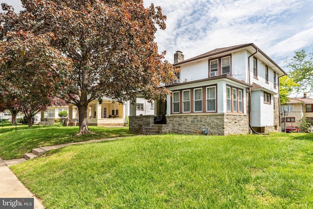 view of front of home featuring a chimney, stucco siding, stone siding, and a front yard