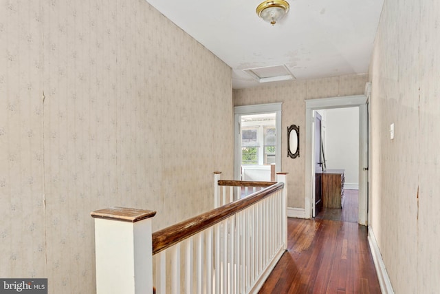 hall featuring wallpapered walls, an upstairs landing, hardwood / wood-style floors, attic access, and baseboards