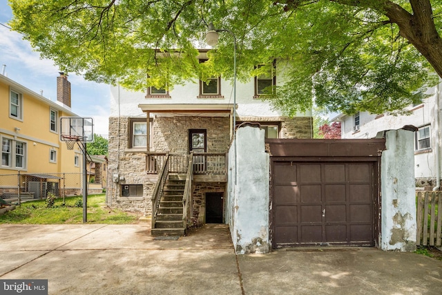 view of front of house featuring stone siding, fence, stucco siding, driveway, and a garage