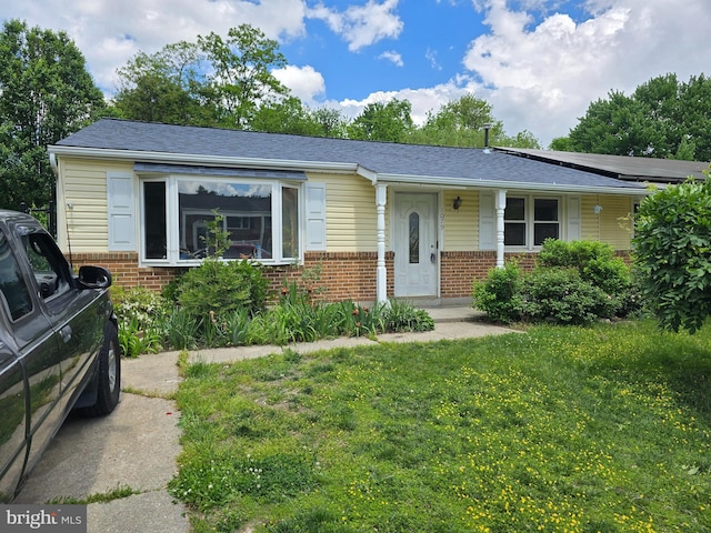 view of front of house with a shingled roof, brick siding, and a front lawn