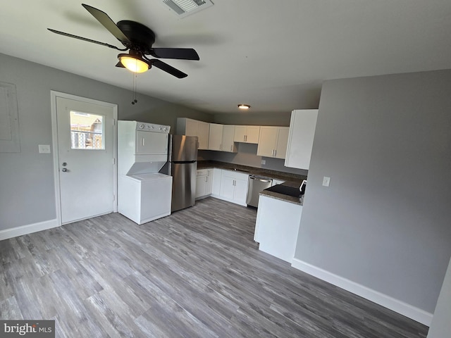 1079 Notley Ct, Pasadena, MD 21122 - kitchen with stacked washing machine and dryer, stainless steel appliances, a ceiling fan, white cabinetry, and wood finished floors