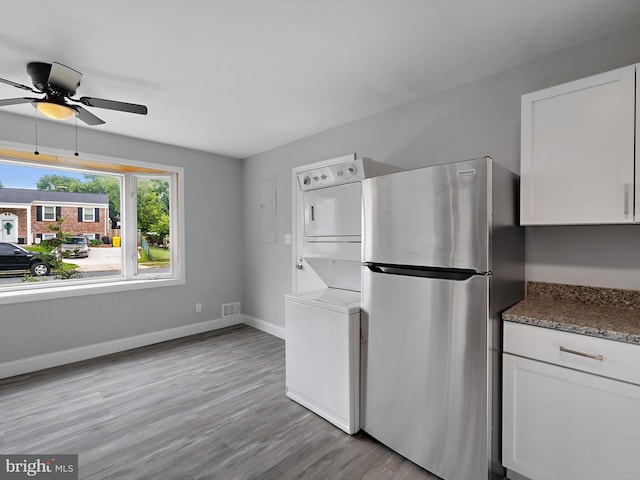 1079 Notley Ct, Pasadena, MD 21122 - kitchen featuring stacked washer / dryer, freestanding refrigerator, ceiling fan, white cabinets, and light wood-style flooring