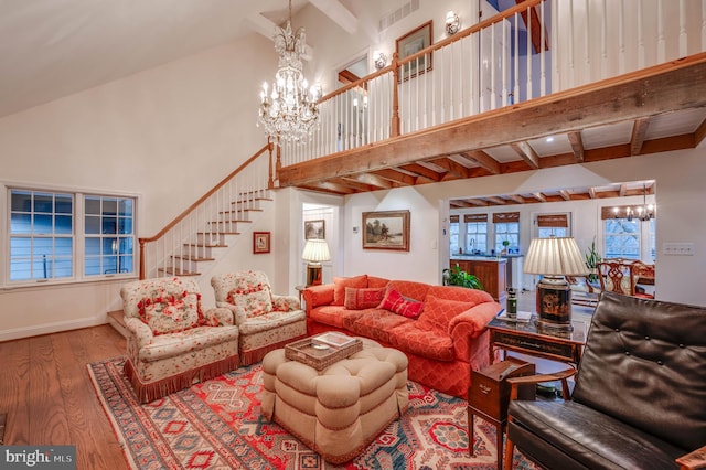 living room featuring a chandelier, wood finished floors, a towering ceiling, stairs, and beam ceiling