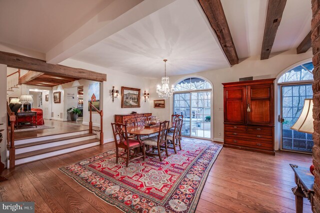 dining room featuring beamed ceiling, hardwood / wood-style flooring, stairs, a chandelier, and plenty of natural light