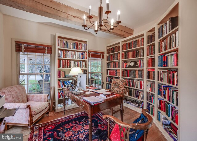 office area featuring wall of books, wood finished floors, and a chandelier