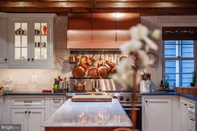 kitchen featuring backsplash, white cabinets, glass insert cabinets, and high end range