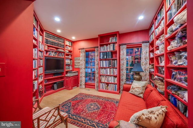 sitting room with wood finished floors, wall of books, and recessed lighting
