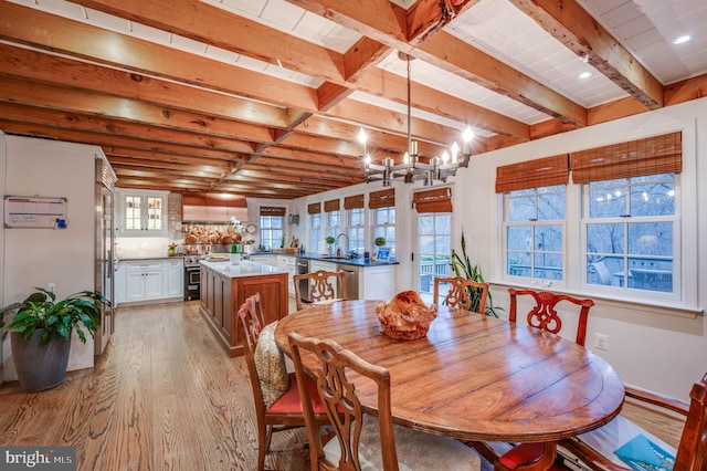 dining area featuring light wood finished floors, a chandelier, and beamed ceiling