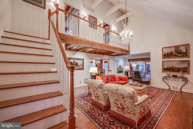 living area with a chandelier, high vaulted ceiling, stairs, wood finished floors, and beamed ceiling