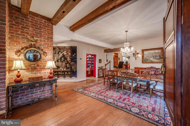 dining room featuring wood finished floors, a chandelier, beam ceiling, and baseboards