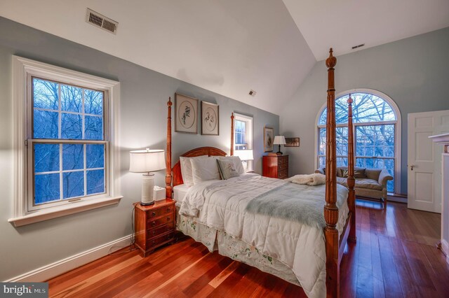 bedroom with multiple windows, hardwood / wood-style floors, baseboards, and high vaulted ceiling