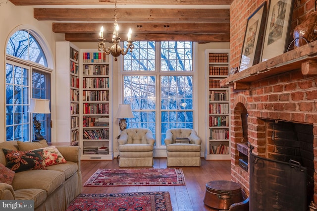 living room with wood-type flooring, a chandelier, a fireplace, beam ceiling, and built in features