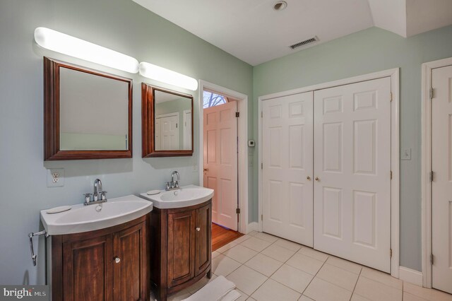 bathroom with two vanities, tile patterned flooring, and baseboards