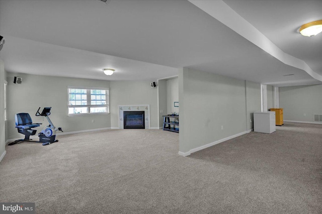 below grade area featuring carpet floors, baseboards, and a glass covered fireplace