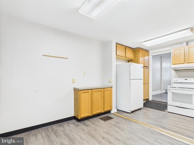 kitchen with white appliances, under cabinet range hood, light wood-style flooring, and light countertops