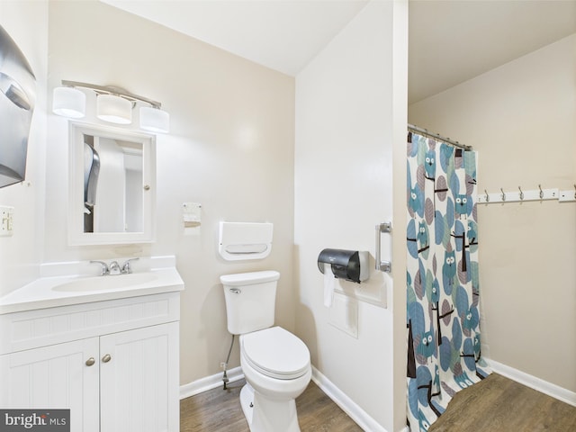 bathroom with wood finished floors, toilet, vanity, a shower with curtain, and baseboards