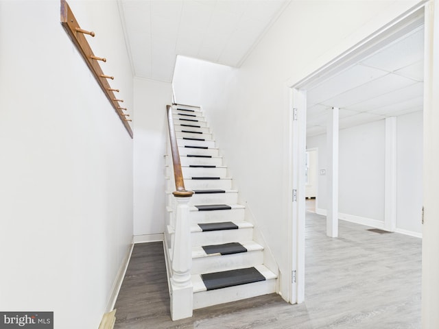 staircase featuring wood finished floors and baseboards