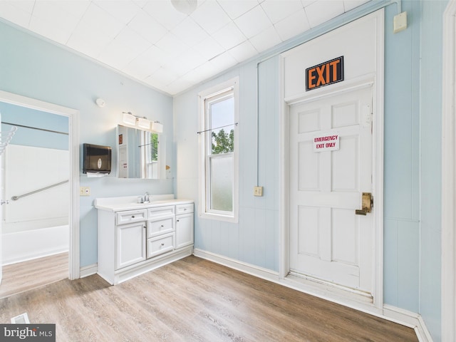 bathroom featuring wood finished floors, vanity, baseboards, and a tub to relax in
