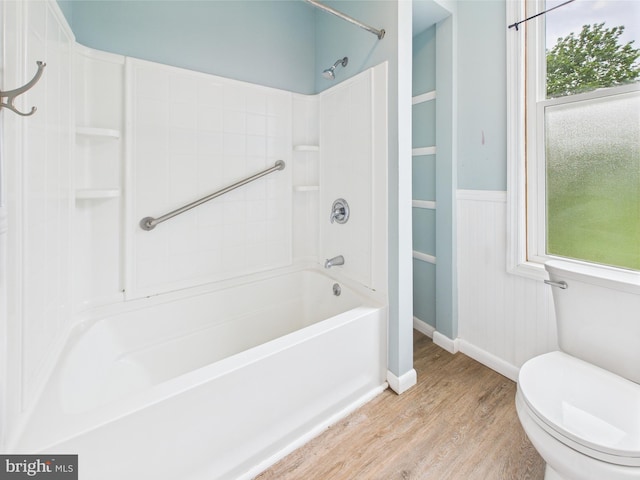 full bathroom featuring toilet, wood finished floors, wainscoting, and tub / shower combination
