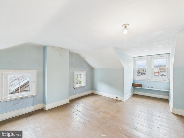 additional living space featuring hardwood / wood-style floors, vaulted ceiling, and baseboards