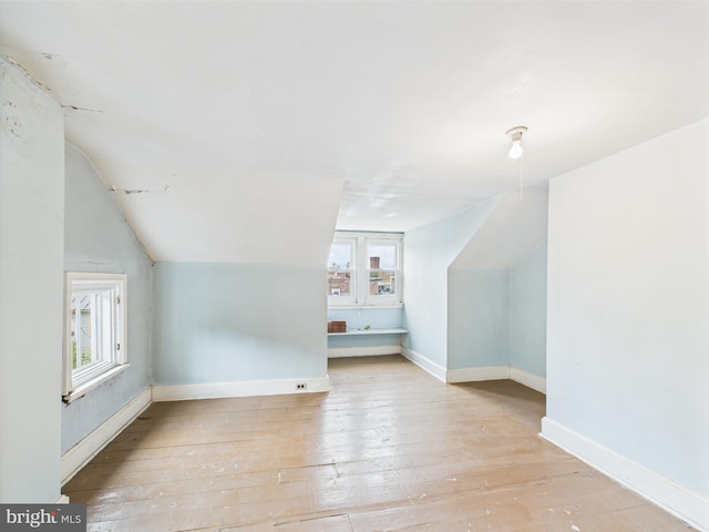 additional living space with lofted ceiling, hardwood / wood-style floors, and baseboards