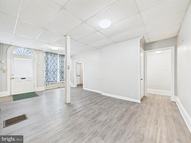 basement with a drop ceiling, wood finished floors, and baseboards