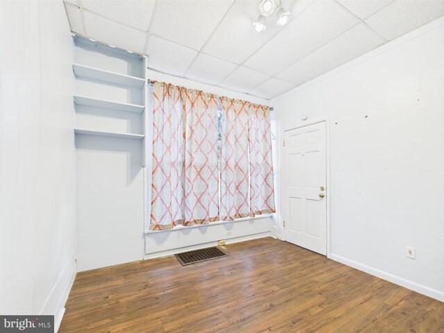 unfurnished room featuring a drop ceiling, wood finished floors, and baseboards