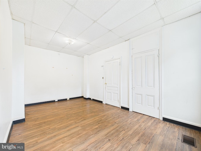 empty room with a drop ceiling, wood finished floors, and baseboards