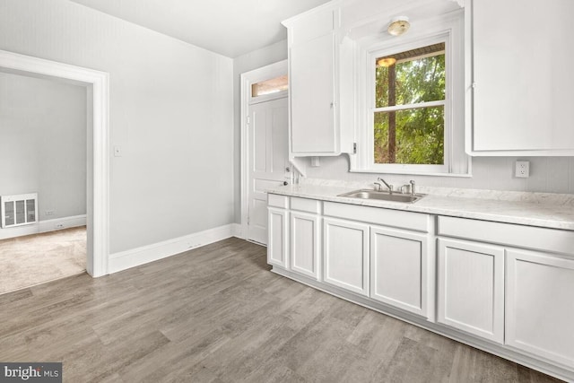kitchen featuring visible vents, a sink, light wood-style floors, light countertops, and white cabinets