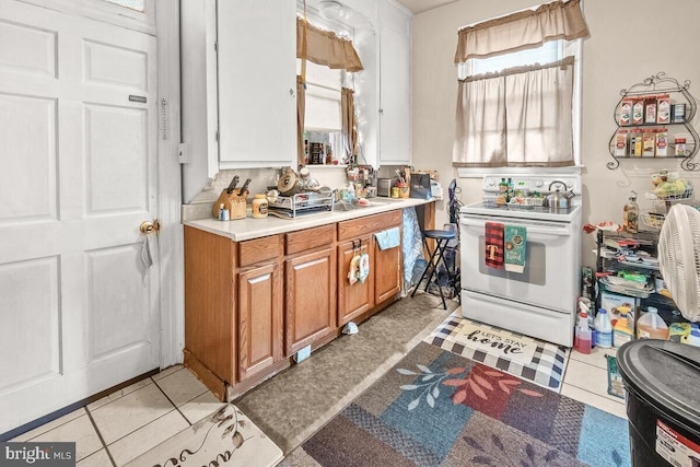 kitchen featuring brown cabinets, light countertops, and white electric range