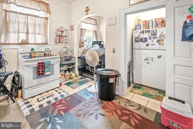 kitchen with arched walkways, white appliances, and tile patterned floors