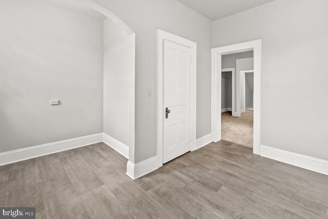 interior space featuring wood finished floors, baseboards, and arched walkways