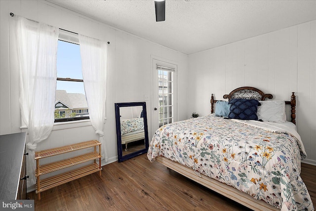 bedroom featuring wood finished floors, a textured ceiling, ceiling fan, and access to outside