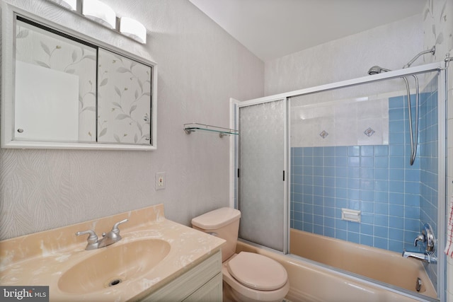 bathroom with vanity, toilet, enclosed tub / shower combo, and a textured wall