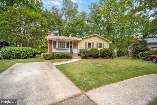 view of front of house with a chimney, a front yard, and brick siding