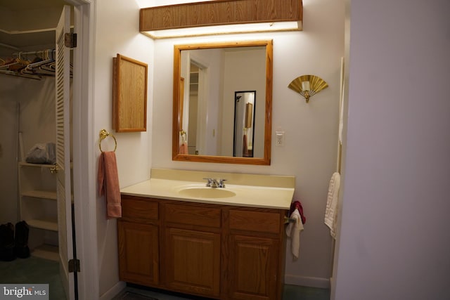 bathroom with vanity and a walk in closet