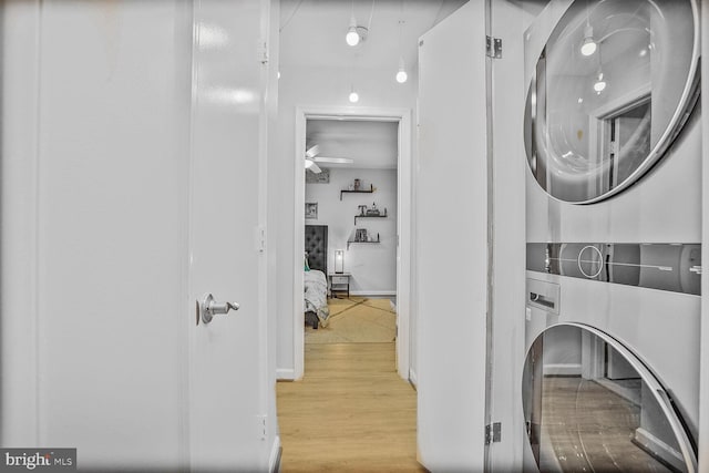 laundry room featuring stacked washer / drying machine, wood finished floors, and ceiling fan