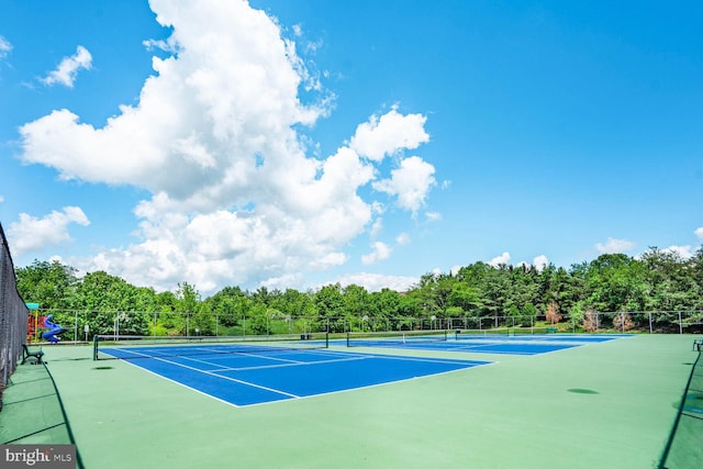 view of tennis court featuring fence and view of scattered trees