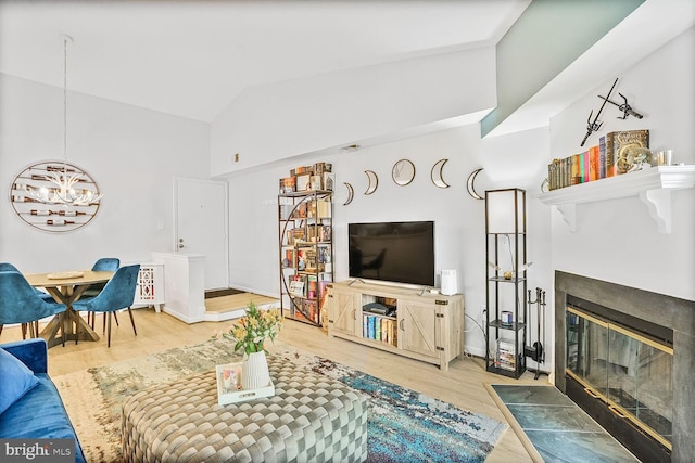 living room with a chandelier, a fireplace with flush hearth, lofted ceiling, wood finished floors, and baseboards
